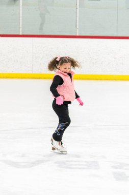 Küçük kız buz pistinde artistik patinaj yapıyor..