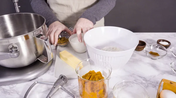 Mixing ingredients in electric kitchen mixer to bake pumpkin spice cupcake.