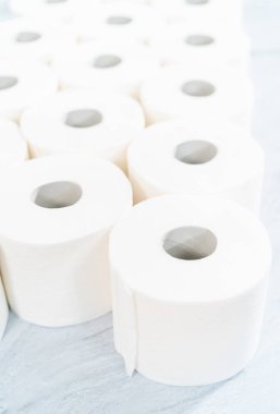 Gri arka planda yeni beyaz tuvalet kağıdı ruloları.