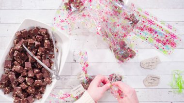 Düz yatıyordu. Adım adım. Ev yapımı macadamia şekerlemesi küçük hediye paketlerine konuyor..