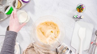 Düz yatıyordu. Adım adım. Vanilyalı Mardi Gras kekleri pişirmek için karışımı elektrikli mikserle karıştırıyorum..