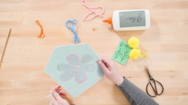 Anne çocuklara el sanatları masasında dikiş setiyle dikiş dikmeyi öğretiyor..