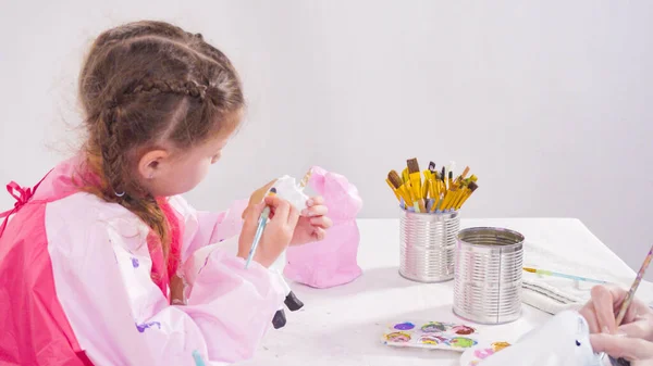 小さな女の子の絵画紙は彼女のホームスクーリングアートプロジェクトのためのアクリル塗料で人形をマッシュ — ストック写真