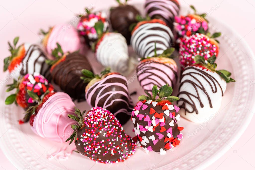Variety of chocolate dipped strawberries on a pink cake stand.