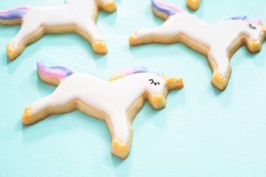 Tek boynuzlu at şeker çerezleri mavi bir arka plan üzerinde kraliyet krema ve gıda glitter ile dekore.