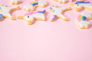 pembe bir arka plan üzerinde kraliyet krema ve gıda glitter ile süslenmiş tek boynuzlu at şeker çerezleri.