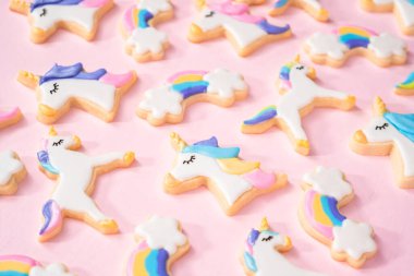 pembe bir arka plan üzerinde kraliyet krema ve gıda glitter ile süslenmiş tek boynuzlu at şeker çerezleri.