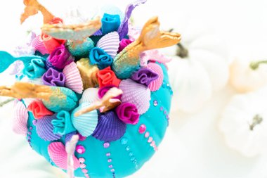 Cadılar Bayramı balkabakları beyaz arka planda deniz kızı kuyruğu, parıltı ve pırıltılı elmaslarla süslenir..