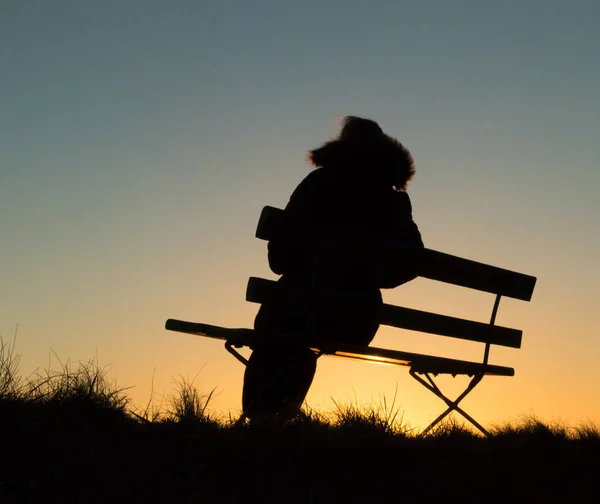 Silhouette d'une personne assise sur un banc au coucher du soleil — Photo