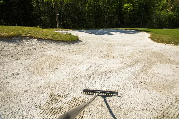 Sand trap, rake in a golf course sand bunkers, raking the sand