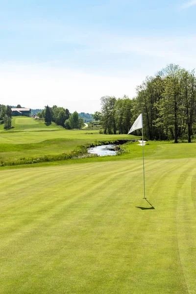 Campo de golf. Agujero con bandera blanca en un día soleado — Foto de Stock