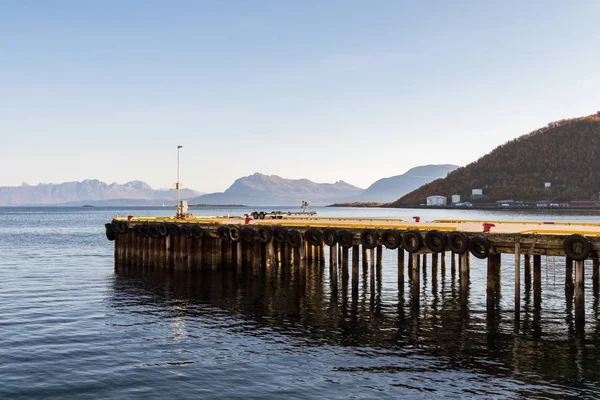 Pier bekleed met banden als spatborden voor de boten, de zee en de bergen in de achtergrond, Harstad in Noorwegen — Stockfoto