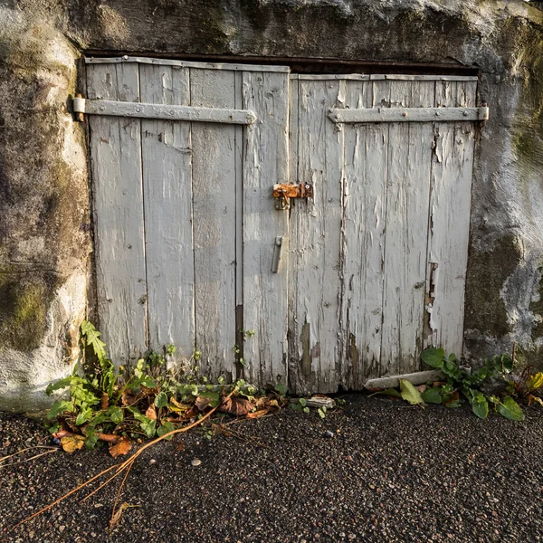 Alte grau lackierte Türen auf einem Steinschuppen — Stockfoto