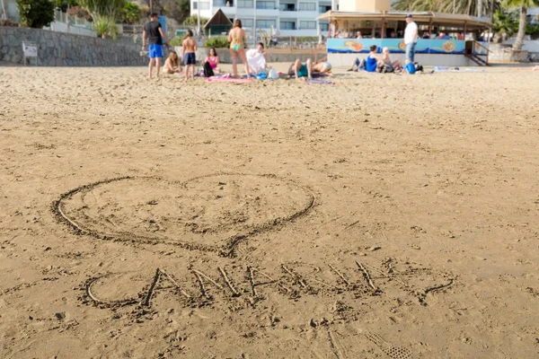 Dibujos en la arena en la playa de Puerto Rico en Gran Canaria, España. Fondo suave con gente en la playa . — Foto de Stock