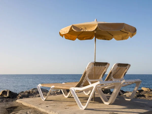 Dos tumbonas y una sombrilla en el rompeolas con vista al Océano Atlántico, Puerto Rico en la isla canaria —  Fotos de Stock