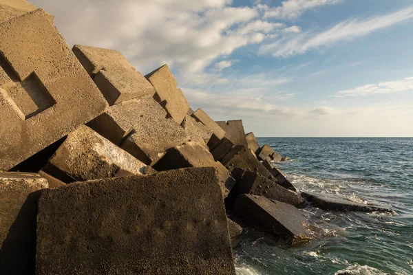 Breakwater blocks in the port of Puerto Rico, Gran Canaria, with the Atlantic Ocean in the background