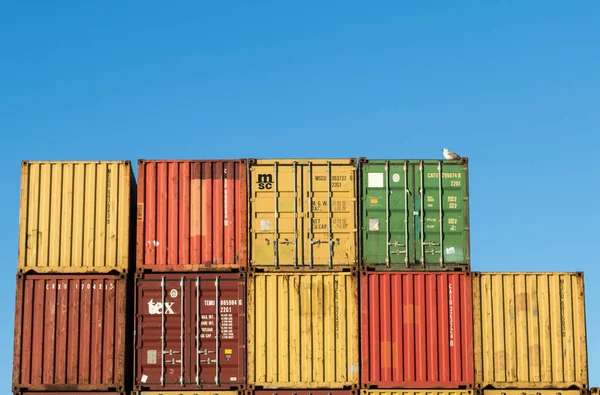 Kristiansand, Norway, November 5, 2017: Stack of containers at the container port in Kristiansand. Yellow, red, green and orange. Blue sky, a gull sitting on top of containers — Stock Photo, Image