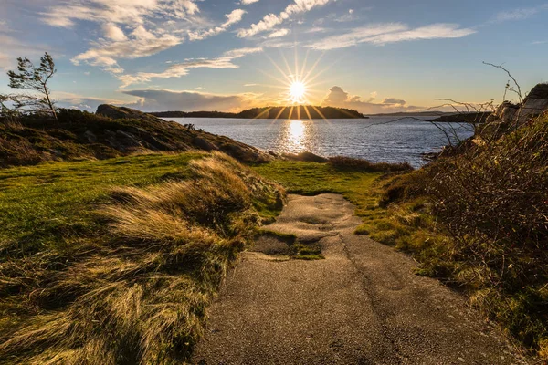 Eine enge, alte Asphaltstraße, die am Meer hält, im Hintergrund der Sonnenuntergang. — Stockfoto