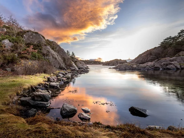 Luz nocturna, océano, piedras y rocas junto al mar, luz cálida y puesta de sol en el fondo . — Foto de Stock