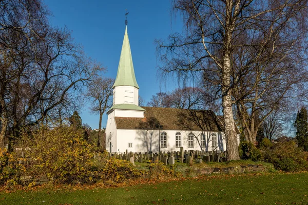 Iglesia de madera blanca vista desde el costado, árboles, hierba y cielo azul en otoño, Kristiansand, Noruega — Foto de Stock
