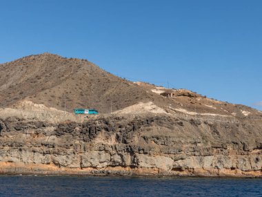 Gran Canaria, İspanya - 16 Aralık Kanarya Adaları. 2016: Mavi otobüs sahilinde sarp dağlarda yolda Puerto de Mogan ve Porto Riko arasında sürüş. Volkanik kaya katmanları. Tabakaları.