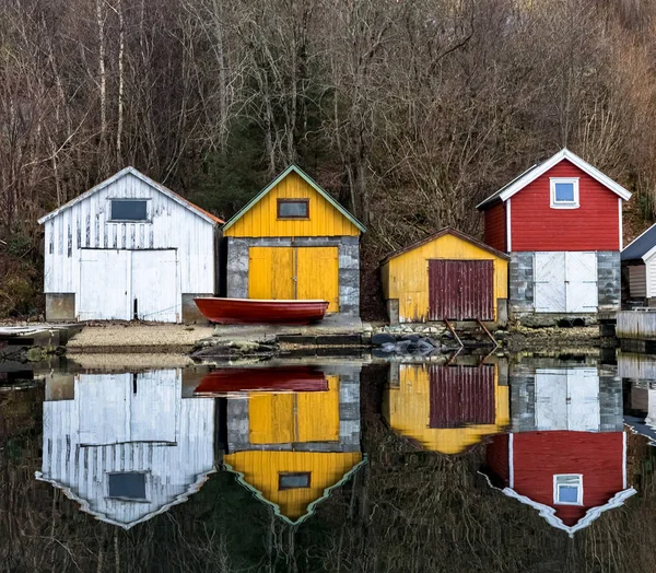Kolnes na Noruega - januray 10, 2018: Quatro antigas casas de barcos de madeira refletidas no oceano calmo. costa oeste norueguesa, Noruega — Fotografia de Stock