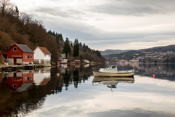 Forresfjord, karmoy in norwegen - 10. januray 2018: ein kleines motorboot, das im wasser im forresfjord ruht. Bootshäuser am Meer. schöner Himmel und blaues Licht — Stockfoto