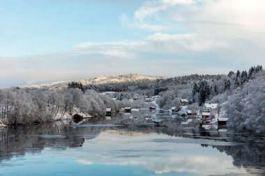 Kristiansand, Norveç - 17 Ocak 2018: Tovdal Nehri, Tveit, doğal manzaralı evler nehir tarafından. Kış saati, ağaçlarda kar. Yansımaları gökyüzünün suda yüzen buz.
