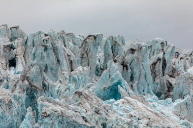 Bir buzul buzu close-up. Blue Ice ile bulutlu gökyüzü yukarıda. Svalbard, Spitsbergen