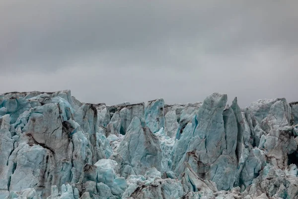 Nahaufnahme des Eises eines Gletschers. blaues Eis mit wolkenverhangenem Himmel darüber. Spitzbergen, Spitzbergen — Stockfoto