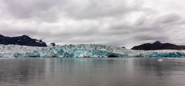 Gletscher trifft auf den arktischen Ozean. Meer, Eis und Berge mit wolkenverhangenem Himmel darüber. Spitzbergen. Panorama — Stockfoto