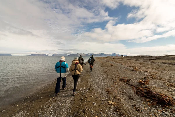 Svalbard, Noruega, 3 de agosto de 2017: Grupo de turistas caminhando na praia de Prins Karls Forland em Svalbard, à procura de morsas . — Fotografia de Stock