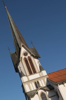 Büyük bir ahşap kilise olan Bamble Kilisesi 'nin kulesinin eğilmiş görüntüsü. Kış, kar, Güneş ve mavi gökyüzü. Dikey görüntü.