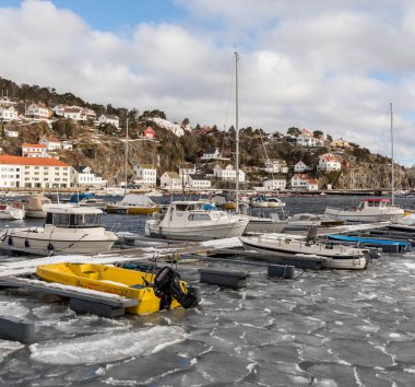 Risør, Norveç - 16 Mart 2018: liman Risør, Norveç'in denizde yüzen buz. Küçük tekne iskelede. Arka plan binalarda.