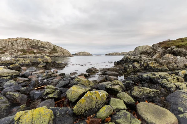 Felsen, die mit Flechten bedeckt sind, das Meer und Inseln im Hintergrund. urd insel im rovaer archipel in haugesund, norwegische westküste. — Stockfoto