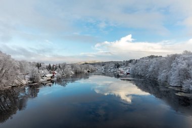 Kristiansand, Norveç - 17 Ocak 2018: Tovdal Nehri, Tveit, doğal manzaralı evler nehir tarafından. Kış saati, ağaçlarda kar. Yansımaları gökyüzünün suda yüzen buz.