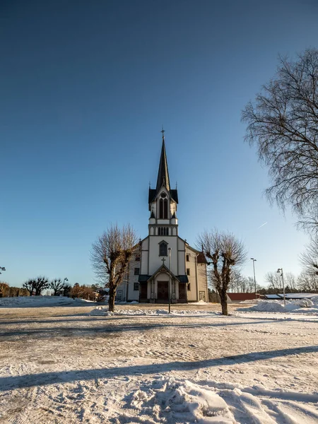 Bamble Church, large wooden church buildt in 1845. Winter, snow, blue sky. Front view. Vertical image.