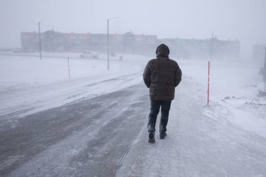 Longyearbyen, Norveç - Mart 2019: Longyear byen 'de kar fırtınası, kar yağışı altında uzaklaşan adam. Svalbard, Norveç