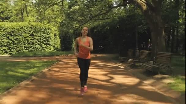 Corriendo mujer corriendo en el parque de la ciudad bajo el sol en hermoso día de verano . — Vídeo de stock