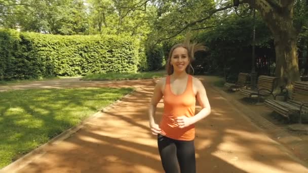 Біг жінка біжить в міському парку на сонці в красивий літній день . — стокове відео
