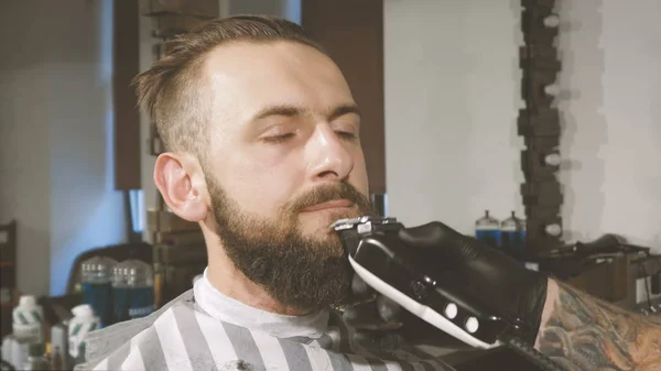 Perfecte vorm krijgt. Zijaanzicht van de close-up van jonge bebaarde man baard kapsel door kapper op barbershop — Stockfoto