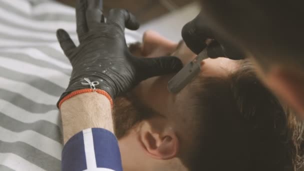 Proces van baarden in Barbershop scheren. Master zorgt ervoor dat een kapsel baard client met vintage scheermes. — Stockvideo