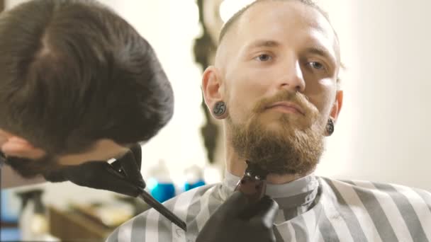 Sto diventando perfetta. Vista laterale da vicino del giovane barbuto che si fa tagliare i capelli dalla barba dal parrucchiere dal barbiere — Video Stock