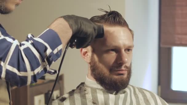 Peinado y corte de pelo para hombre con cortapelos en una peluquería o peluquería — Vídeos de Stock