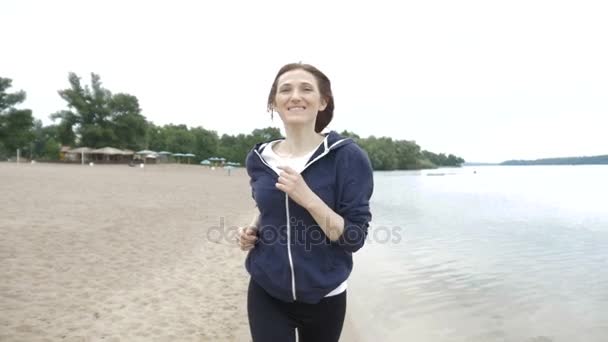 Unga hälsosam livsstil kvinna kör på sunrise beach. Flicka kör på sand nära vatten på stadens strand. — Stockvideo
