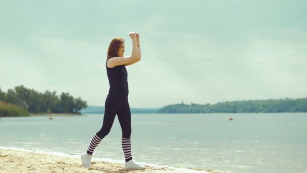 Vacker rödhårig flicka gör övningar på floden. — Stockvideo