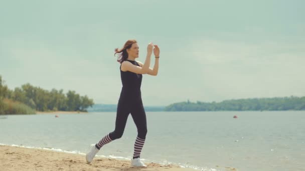 Beautiful red-haired girl doing exercises on the river. — Stock Video