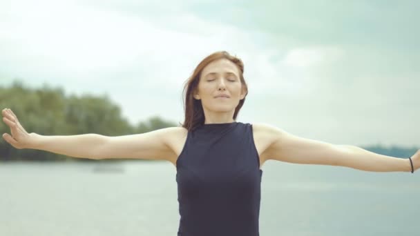 Belle fille aux cheveux roux faisant des exercices sur la rivière . — Video