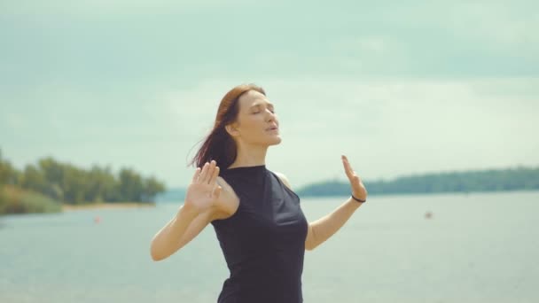 Krásná rusovlasá dívka dělá cvičení na řece. — Stock video