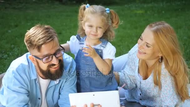 Vacances d'été, concept famille, enfant et technologie - famille souriante au parc avec tablette pc — Video